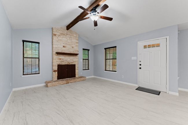Unfurnished living room with ceiling fan, plenty of natural light, a fireplace, and light marble finish floors | Image 15