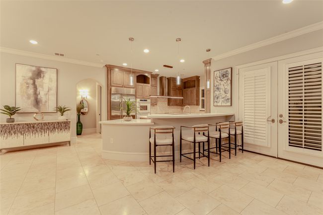 Kitchen with arched walkways, white oven, stainless steel built in fridge, light countertops, and recessed lighting | Image 32