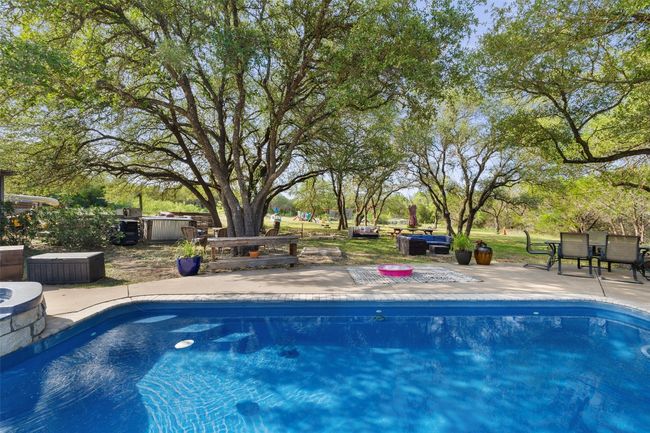 Swimming pool featuring a patio area, a jacuzzi, and view of scattered trees | Image 11
