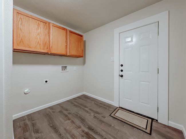 Laundry area with electric dryer hookup, hookup for a washing machine, wood finished floors, and cabinet space | Image 29