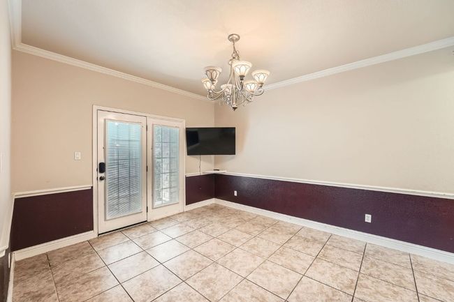 Unfurnished dining area featuring crown molding, light tile patterned flooring, baseboards, and an inviting chandelier | Image 11