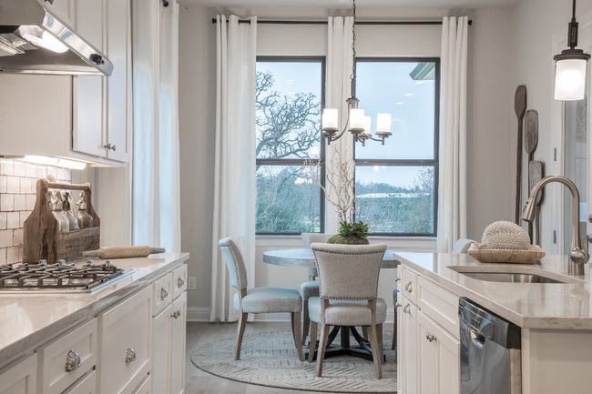 Kitchen with appliances with stainless steel finishes, a sink, under cabinet range hood, white cabinets, and light stone countertops | Image 11