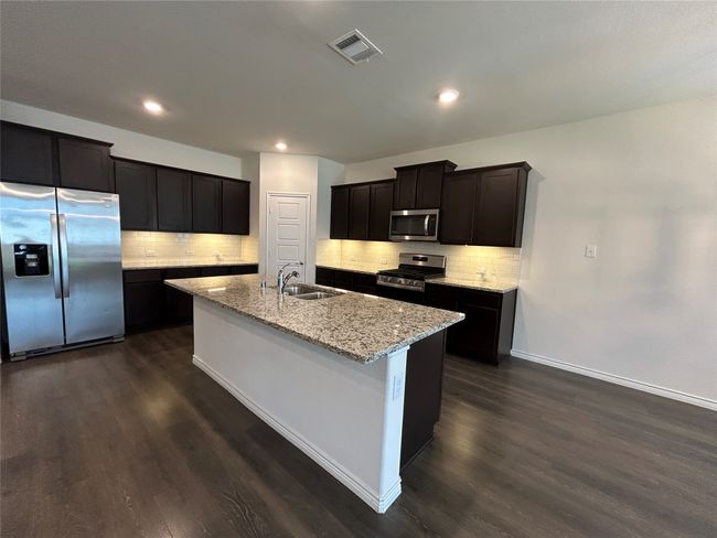 Kitchen with appliances with stainless steel finishes, a sink, dark wood-style flooring, a center island with sink, and recessed lighting | Image 5