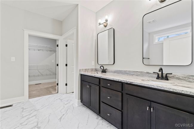 Photo represents the plan, not the actual home. Design selections may vary. The first-floor primary suite includes a walk-in closet and an ensuite bath featuring a double vanity, a tiled walk-in shower, a water closet, and a linen closet. | Image 6