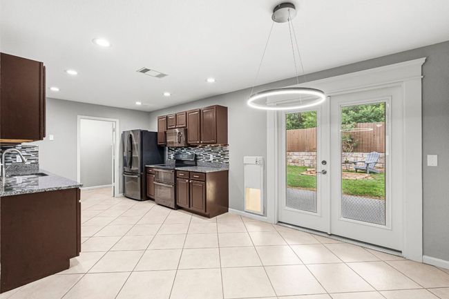 Kitchen with double oven range, decorative backsplash, dark brown cabinets, refrigerator with ice dispenser, and stainless steel microwave | Image 8