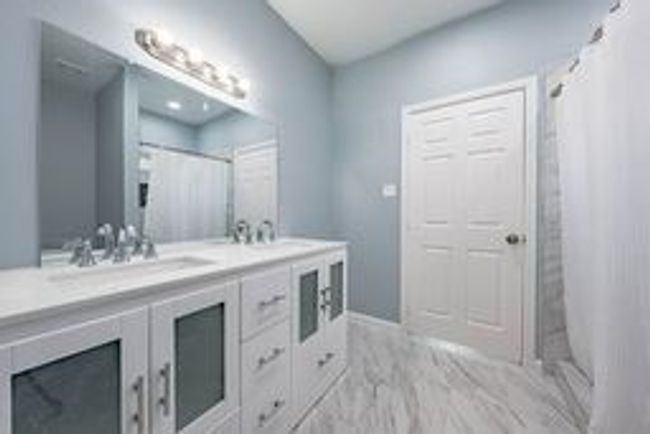 Bathroom featuring a shower with curtain, a sink, and double vanity | Image 18