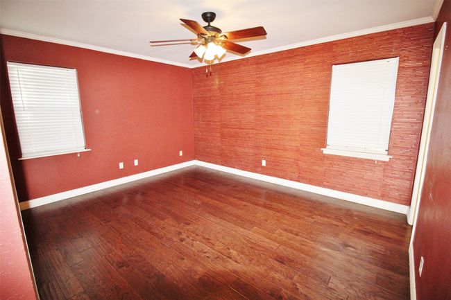 Spacious primary bedroom with wood flooring | Image 17