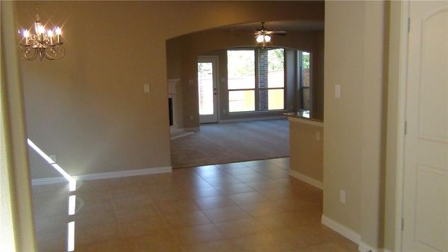 Unfurnished dining area with arched walkways, baseboards, a ceiling fan, light colored carpet, and a chandelier | Image 4