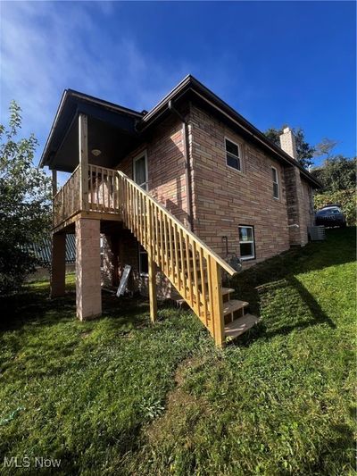 Rear view of property featuring a wooden deck, a yard, and central air condition unit | Image 3