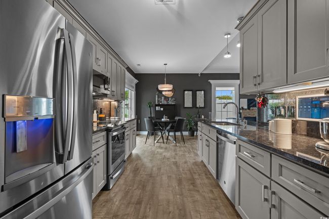 Kitchen with stainless steel appliances, gray cabinets, backsplash, and dark wood-style flooring | Image 16