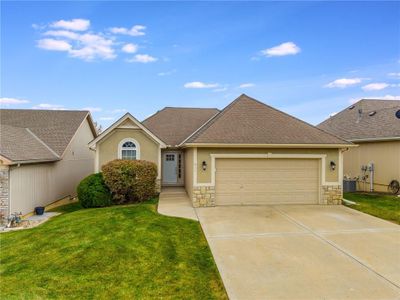 View of front of property featuring central air condition unit, a front yard, and a garage | Image 1