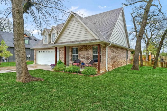 View of front of home featuring concrete driveway, fence, an attached garage, a front yard, and brick siding | Image 6