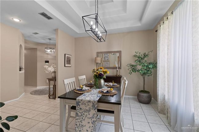 Dining room with a raised ceiling, light tile patterned flooring, and baseboards | Image 10