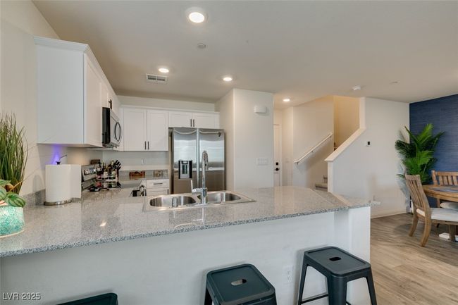 Kitchen featuring recessed lighting, a peninsula, white cabinetry, stainless steel appliances, and a sink | Image 13