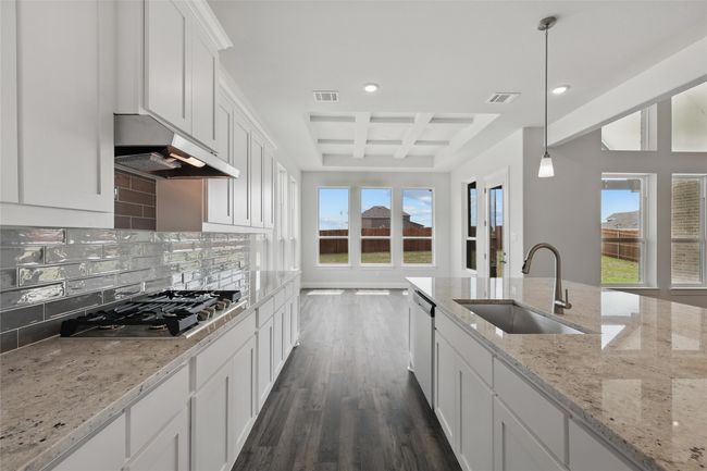 Kitchen featuring coffered ceiling, visible vents, stainless steel appliances, a sink, and backsplash | Image 5