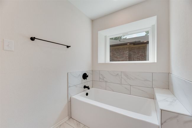 Bathroom with a garden tub, marble look tile flooring, and baseboards | Image 14