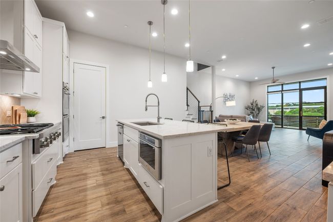 Elegant chef's kitchen with center island, Thermador gas stove, double oven, built in Jenn Air microwave, under cabinet lighting, wine fridge, and pantry. | Image 9