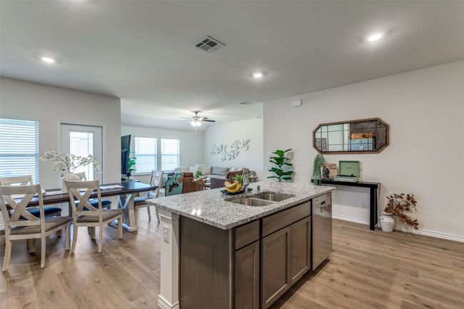 Kitchen View 4 featuring dishwasher, a sink, light laminated wood-plank floors, a kitchen island with sink, and open floor plan | Image 10