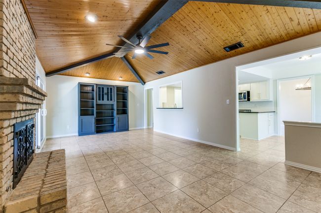 Unfurnished living room featuring wooden ceiling, light tile patterned floors, a fireplace, and ceiling fan | Image 9