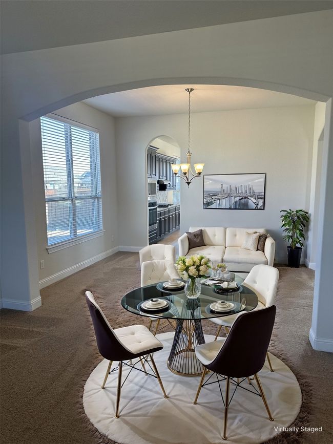 Carpeted dining room with baseboards, arched walkways, and a chandelier | Image 5
