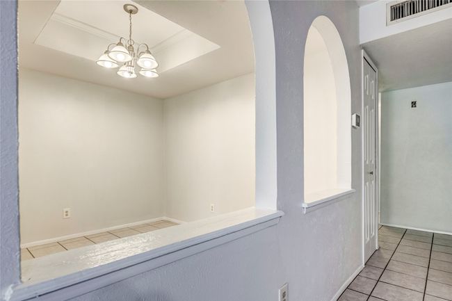 Hall featuring tile patterned flooring, a raised ceiling, arched walkways, and a chandelier | Image 15
