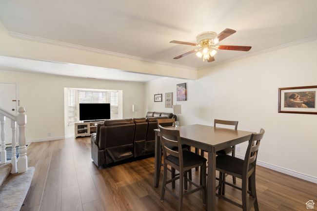 Dining area featuring dark wood-style floors, crown molding, baseboards, and a ceiling fan | Image 5