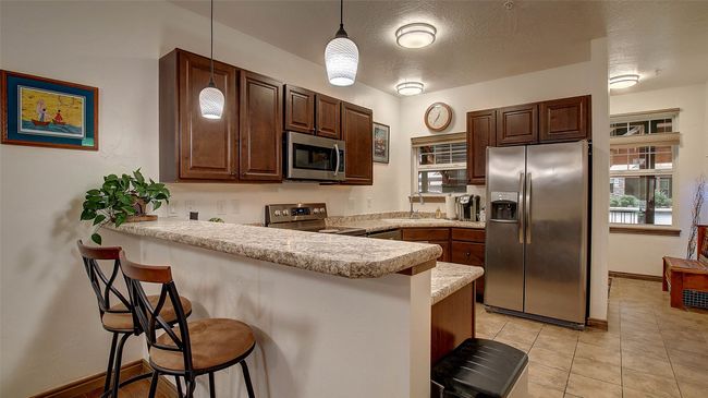 Kitchen with breakfast bar, range, refrigerator, dishwasher, microwave and plenty of storage | Image 4