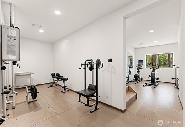 Utility room in basement is versatile for all manner of uses. Virtually staged here as a home gym (Floor of basement is concrete, not wood). | Image 37