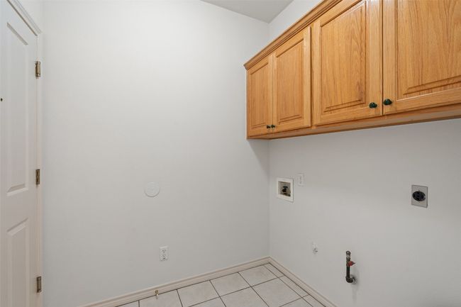 The laundry room has cabinet storage for detergents and more. | Image 25