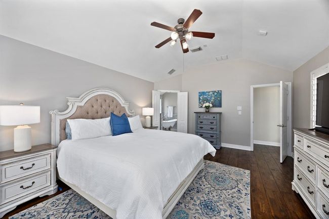 Oversized primary suite is tucked in the back of the home with neutral paint, plantation shutters, and access to the backyard. | Image 25