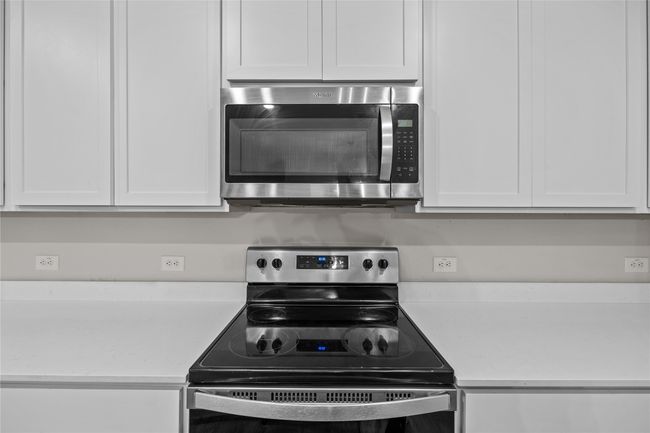 Kitchen featuring stainless steel appliances, light countertops, and white cabinets | Image 16