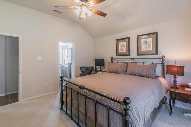 Bedroom featuring visible vents, baseboards, vaulted ceiling, light carpet, and ensuite bathroom | Image 21