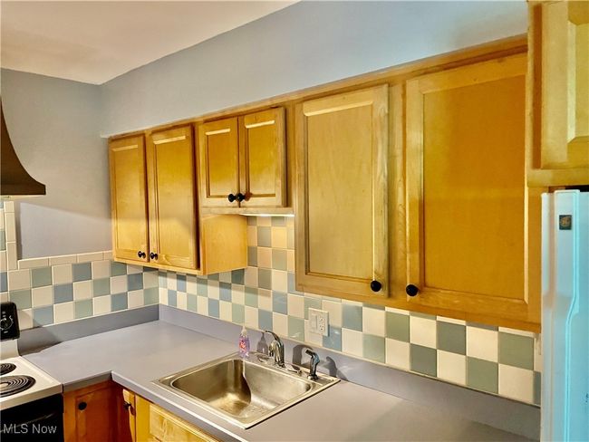 Kitchen featuring range with electric stovetop, a sink, tasteful backsplash, freestanding refrigerator, and light countertops | Image 12
