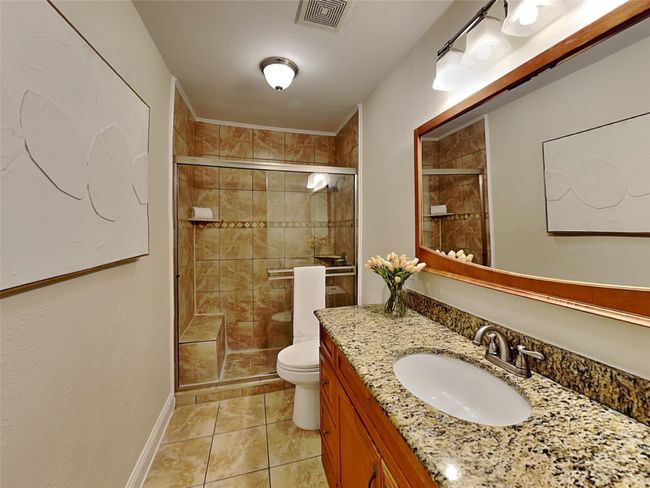 Full bathroom featuring tile patterned flooring, visible vents, toilet, vanity, and a stall shower | Image 7