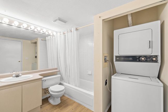 Full bathroom with shower / bath combo, wood finished floors, toilet, stacked washer and clothes dryer | Image 12