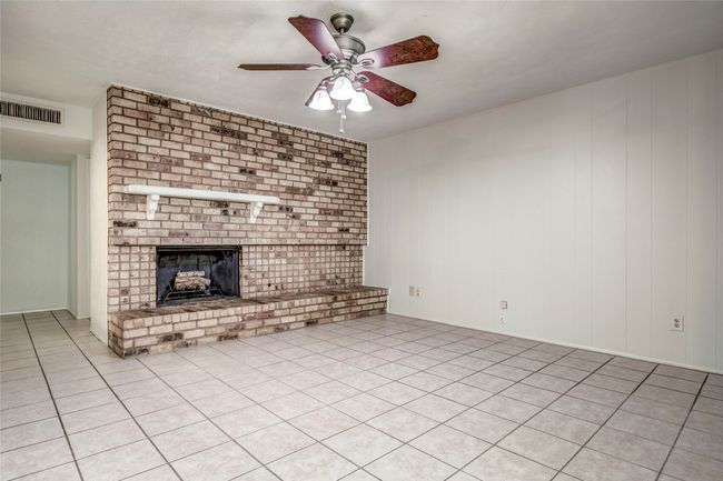 Unfurnished living room featuring a ceiling fan, a brick fireplace, and light tile patterned floors | Image 18