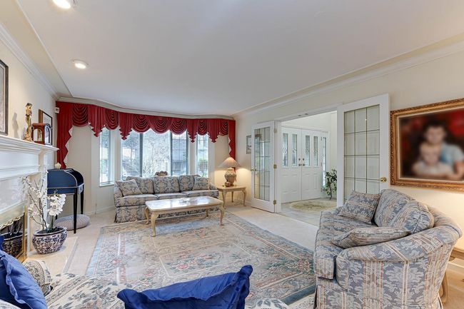 Carpeted living area with baseboards, ornamental molding, french doors, and a glass covered fireplace | Image 5