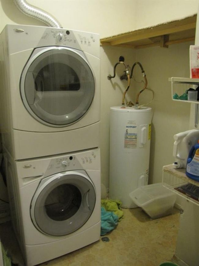 Washroom with water heater, stacked washer / dryer, and laundry area | Image 9