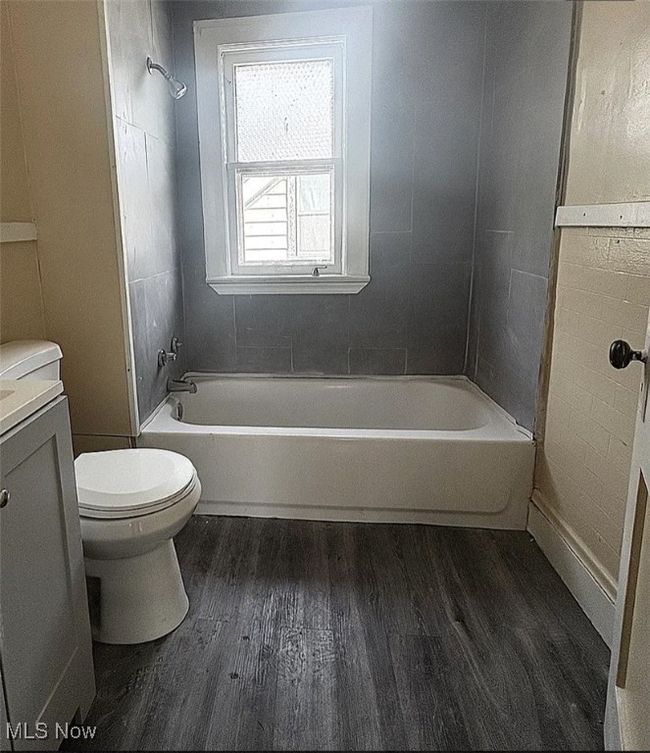 Full bath featuring toilet, vanity, bathing tub / shower combination, and wood finished floors | Image 8