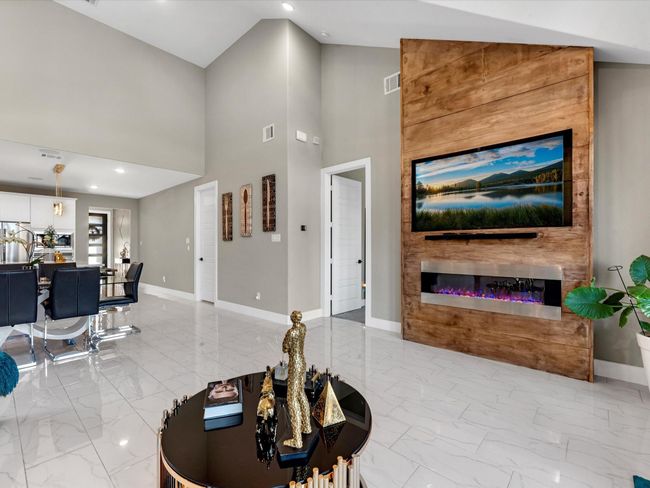 The room boast an open layout connecting the living room and dining areas for spacious feel, the soft neutral paint colors making the room feel modern and versatile. Encasing a focal point a built in beautiful accent wall wall to display the tv and elegant modern electric chimney wit a built in surround system for the family to enjoy creating lifestyle memories! | Image 21