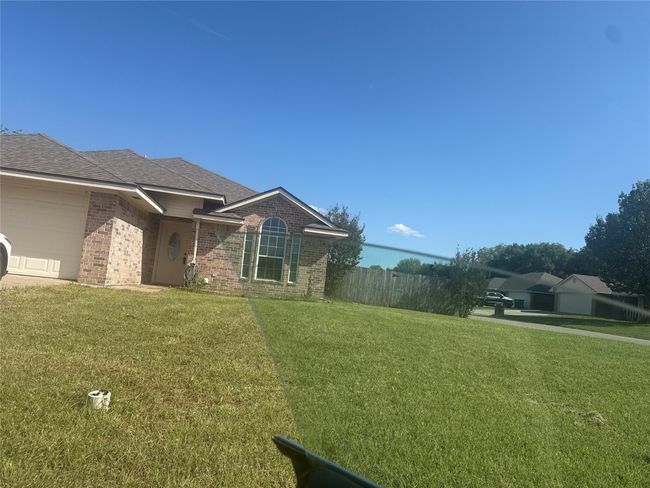 View of property exterior featuring brick siding, an attached garage, and a shingled roof | Image 4