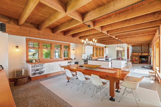 Dining room featuring radiator heating unit, wooden ceiling with exposed beams, a chandelier, a wood stove, and speckle patterned floor | Image 9