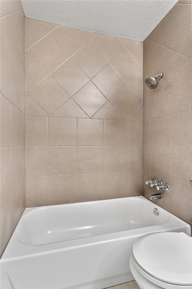 The tub/shower combo has a modern tile design. | Image 22