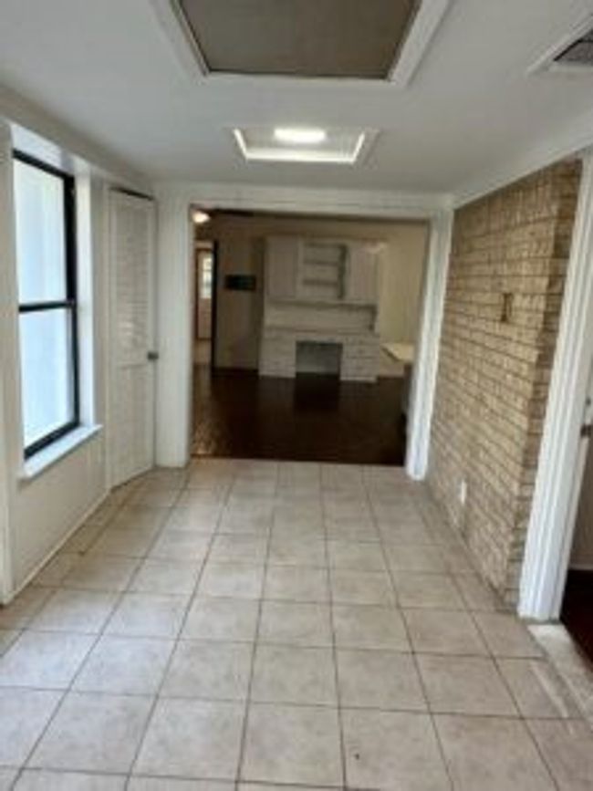 Corridor featuring brick wall, attic access, and light tile patterned floors | Image 5