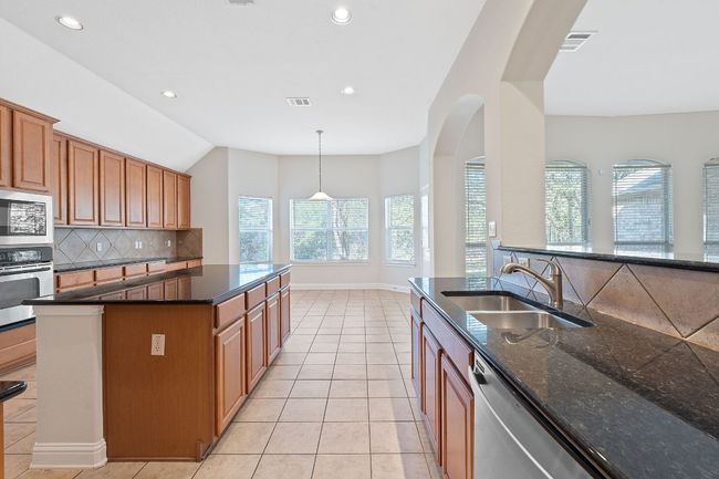 Kitchen featuring a sink, appliances with stainless steel finishes, light tile patterned floors, visible vents, and decorative backsplash | Image 8
