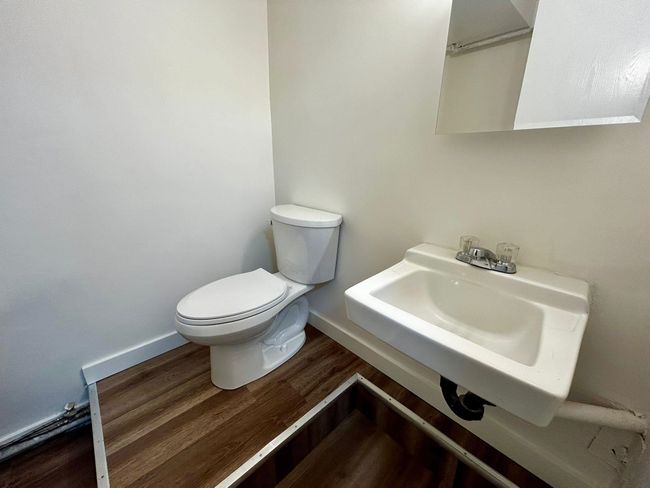 Bathroom featuring baseboards, wood finished floors, a sink, and toilet | Image 6