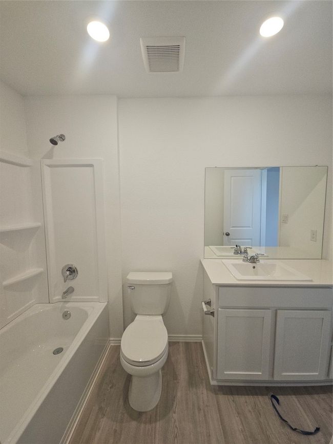 Bathroom featuring wood finished floors, vanity, toilet, baseboards, and shower / bath combination | Image 23
