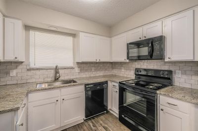 Kitchen with white cabinets, hardwood / wood-style flooring, black appliances, and sink | Image 3