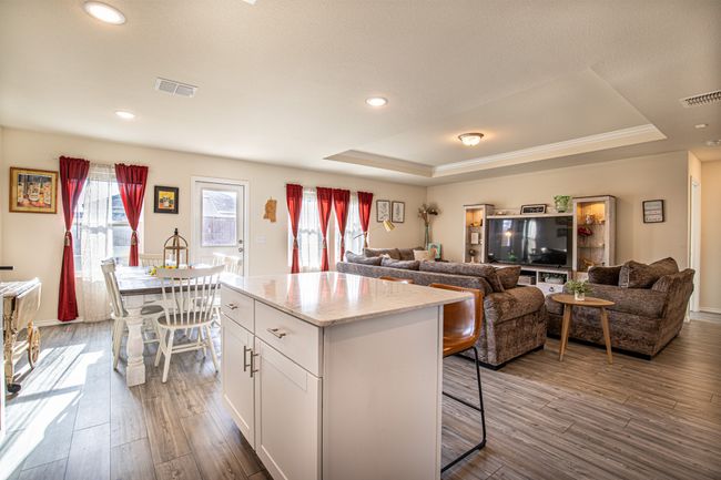 Kitchen featuring a tray ceiling, dark wood-style floors, white cabinets, a kitchen breakfast bar, and healthy amount of natural light | Image 6