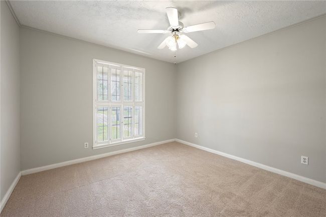 Empty room with carpet flooring, baseboards, a textured ceiling, and ceiling fan | Image 15